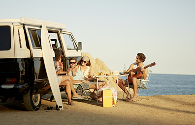 Van life: people gathered around a camper at the beach