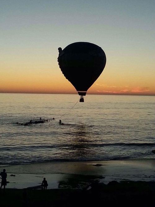 Lifeguards tow a stricken hot air balloon into shore. (Twitter)
