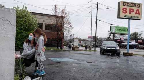 Mallory Rahman and her daughter Zara Rahman, 4, who live nearby, pause after bringing flowers to the Gold Spa massage parlor in Atlanta.