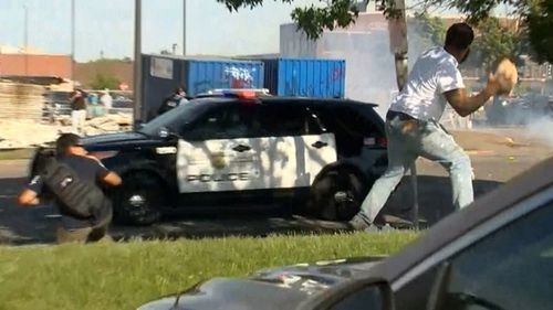 A protester hurls a huge rock at a police car after a stabbing during Minneapolis riots.