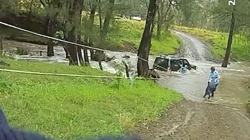 A police officer has rescued three people from a car stranded in floodwaters