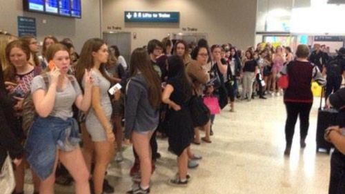 Excited teenage girls wait patiently for the arrival of One Direction and 5 Seconds of Summer at Sydney Airport. (Twitter)