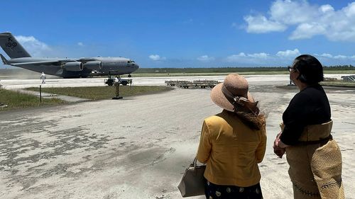 Australian High Commissioner to Tonga, Ms Rachael Moore (left), standing with Tongan Foreign Minister, Fekitamoeloa 'Utoikamanu, watching the arrival of the first Royal Australian Air Force C-17A Globemaster III aircraft from Australia delivering humanitarian assistance.