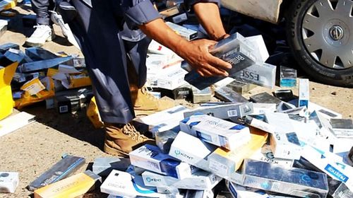 Militants prepare to burn a pile of confiscated cigarettes.