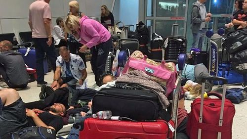 Passengers try to rest on the floor at a terminal in JFK Airport. (Twitter)