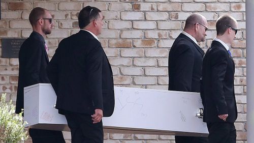 Father Peter Beilby (second from right) and brother Nathan Beilby (left) assist pallbearers with the casket. Picture: AAP