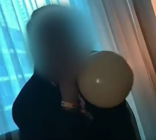 A schoolie breathes in what looks like a balloon, believed to be full of the potential deadly nitrous oxide – or "nang".