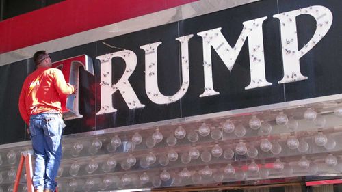A worker removes letters from a logo at one of Donald Trump's failed casinos.