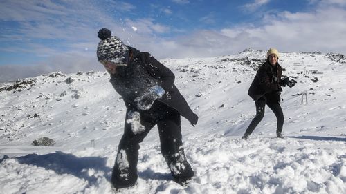 Isamar Fontes (right) from Brazil with friend Ian Costa admiring the view and the snow from the top of the Kosciuszko Express Chairlift ahead of today's opening of the snow season for skiers and snowboarders at the Thredbo ski resort.