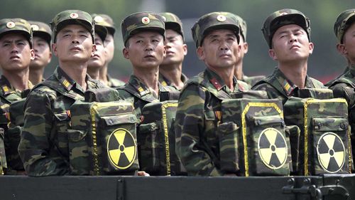 North Korean troops carrying bags bearing a nuclear logo at a parade. (AAP)