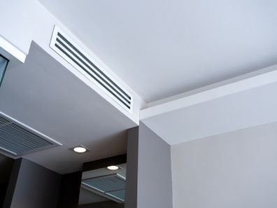 From bottom view of air conditioning wall mounted ventilation system on ceiling in white clean hotel guest room background. Hotel room air ventilation grill on the wall.