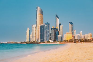 Panoramic view of stunning sandy beach near Corniche seaside embankment with great sunset view of Abu Dhabi, UAE towering skyscrapers