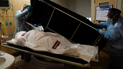 Transporters Miguel Lopez, right, Noe Meza prepare to move a body of a COVID-19 victim to a morgue at Providence Holy Cross Medical Center in the Mission Hills section of Los Angeles Saturday, Jan. 9, 2021. (AP Photo/Jae C. Hong)