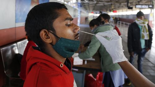 2021년 12월 3일 금요일 인도 아마다바드의 기차역에서 의료 종사자가 COVID-19 테스트를 위해 도시에 입국하는 여행자의 면봉 샘플을 채취합니다.