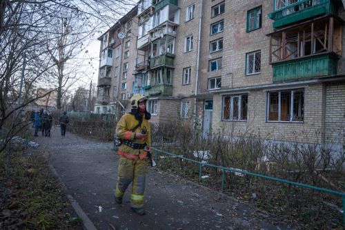 A firefighter examines damage in an apartment building following a Russian drone attack in Kyiv, Ukraine, Saturday, Nov. 25, 2023