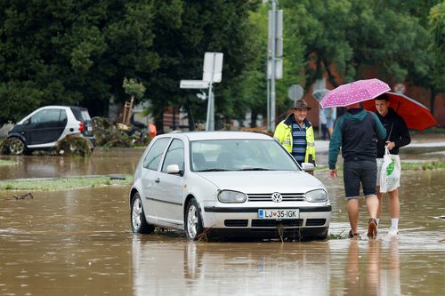 People stand next to a car during floods in Medvode, Slovenia, August 4, 2023. REUTERS/Borut Zivulovic