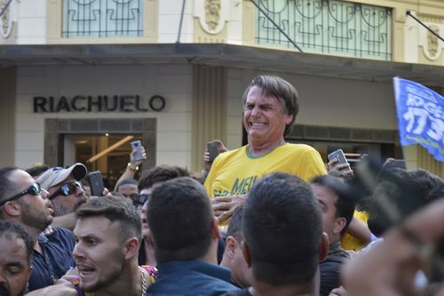 The right-winger grimaces as he's knifed in the abdomen while being carried on supporters' shoulders.