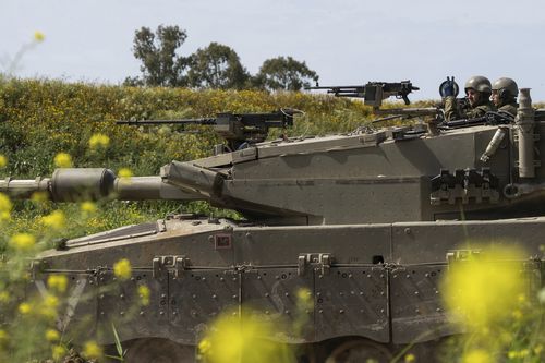 Des soldats israéliens se déplacent sur le dessus d'un char près de la frontière entre Israël et Gaza, vu du sud d'Israël, le jeudi 21 mars 2024. 