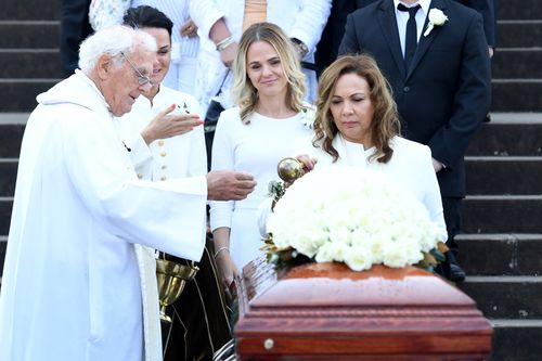 Les Murray's partner Maria (right) blesses the casket as his daughters Tania (left) and Natalie look on following his State Funeral at St Mary's Cathedral. (AAP)