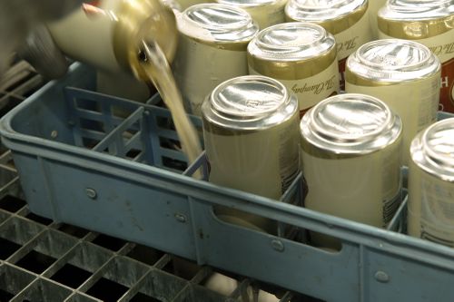 کارگری محتویات قوطی های آبجو میلر های لایف را قبل از له شدن در کارخانه Westlandia در Ypres، بلژیک، دوشنبه، 17 آوریل 2023، می ریزد.  