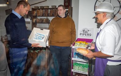 Prince William, Duke of Cambridge is presented with a birthday cake by shop owner Paul Brandon (right) during a visit to Smiths the Bakers, in the High Street on June 19, 2020 in King's Lynn, Norfolk.