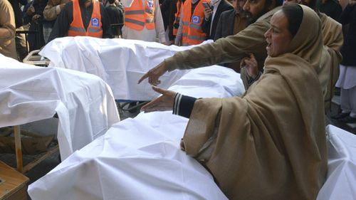 A woman mourns next to the coffin of her family member, who was killed in the suicide bombing inside a mosque, at a hospital, in Peshawar.