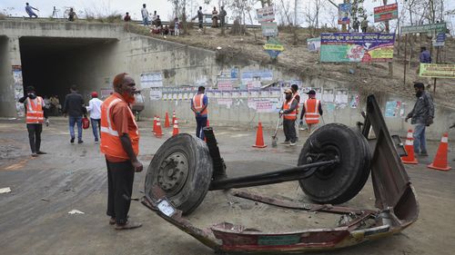 I volontari si trovano vicino al relitto di un autobus caduto in un fosso lungo la strada nel distretto di Chapchar del distretto di Madaripur, Bangladesh, domenica 19 marzo 2023. 