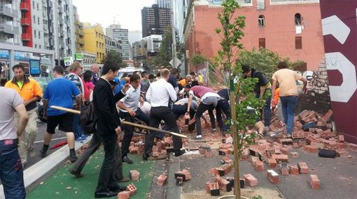 Passersby rush to clear the debris from the wall collapse. 