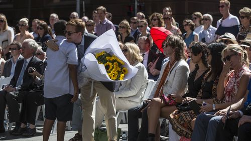 Local school student Jack Tighe hugged Mr Johnson's partner, Thomas  Zinn, after presenting the bouquet of sunflowers. (AAP)