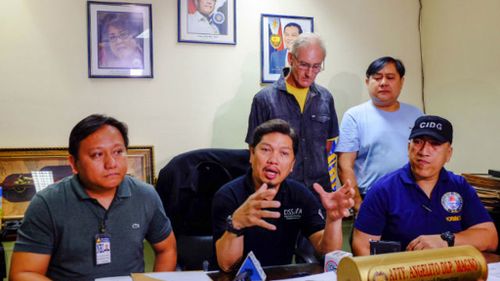 Peter Gerard Scully stands behind investigators from the National Bureau of Investigation. (Source: Rappler)