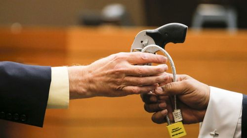 Criminal scene analyst Ross Martin Gardner (left) hands the gun used in the shooting of Diane McIver back to Fulton County Chief Assistant District Attorney Clint Rucker (right)