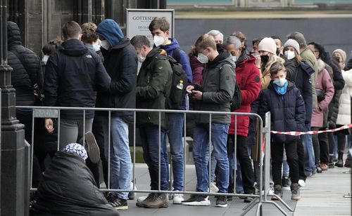 Le persone che indossano le maschere obbligatorie si mettono in fila per entrare nella cattedrale di Colonia, in Germania, venerdì 7 gennaio 2022. 