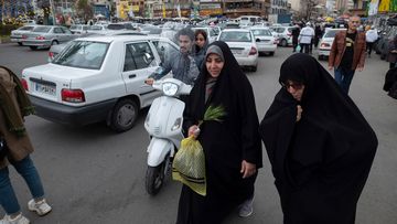 A veiled Iranian woman walks along a square with her relative in northern Tehran on March 17.