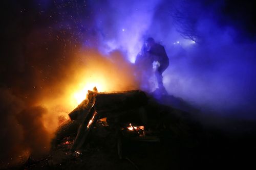 A protester, who planned to stop buses carrying passengers evacuated from the Chinese city of Wuhan, kindles a fire outside Novi Sarzhany.