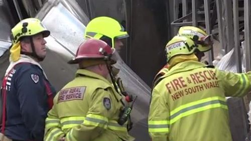 Fire crews inspect the wreckage of the truck on the embankment.