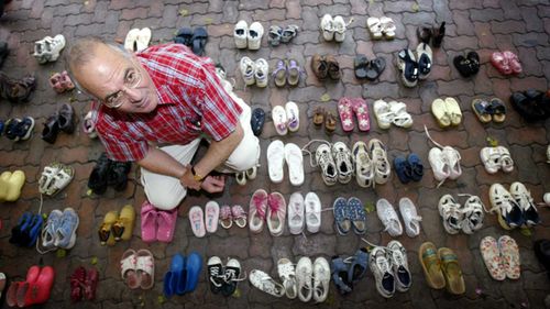 Tony Kevin, author of "A Certain Maritime Incident", sits amongst the 146 pairs of shoes, with each pair representing a child that drowned when the ship Siev-X sank on its way to Christmas Island.