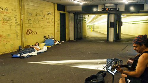 Rough sleepers and a busker are pictured at Sydney's St James Station during the coronavirus lockdown.