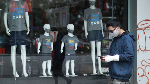 A man walks past the display window of a clothing store in Hanoi, Vietnam on Thursday, Apr. 23, 2020. Business activities have begun to resume in Vietnam as the country lifts the nationwide lockdown to contain the spread of COVID-19. (AP Photo/Hau Dinh)