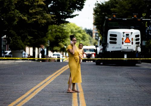 A woman holding a baby stands outside the Oregon District crime scene the 400 block of E. Fifth Street in Dayton , Ohio. Ten people where killed, including the gunman, and 26 injured in a mass shooting.