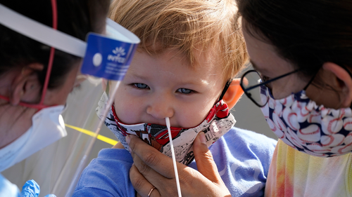 Penny Brown, two, is held by her mother, Heather Brown, as her nose is lightly swabbed during a test for COVID-19 at a new walk-up testing site at Chief Sealth High School, Friday, Aug. 28, 2020, in Seattle.  (AP Photo/Elaine Thompson)