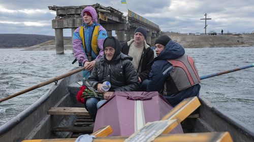 A woman sits in a boat crossing the Siverskyi-Donets river near Staryi-Saltiv, Kharkiv region on Wednesday Jan. 4, 2023, transporting the coffin containing her dead son, a soldier who was killed in fighting with Russians. (AP Photo/Erik Marmor)