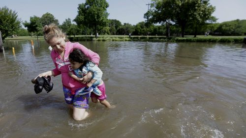 Nayeli Cervantes carries her friend's daughter Sophia Aviles through the floodwaters outside their apartment in Houston. (AAP)