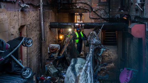 Police and workers inspect the building where at least 12 people died in a fire in the Bronx borough of New York.