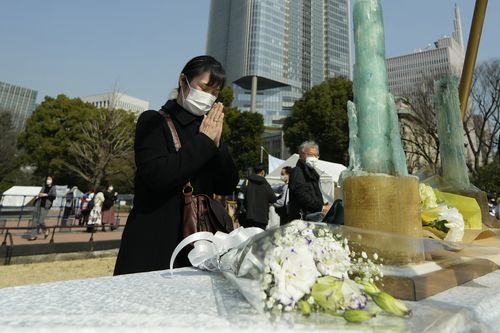 A visitor prays at a makeshift altar to mourn for the victims of the March 11, 2011 earthquake and tsunami during a special memorial event Friday, March 11, 2022, in Tokyo, Japan 