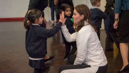 The Duchess high-fives a happy student. (Getty Images)