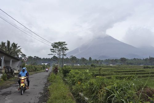 Kierowcy jadą wiejską drogą, gdy góra Semeru wyrzuca dym wulkaniczny w Lumagang, East Java, Indonezja, niedziela, 17 stycznia 2021 r.