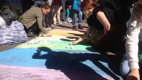 Protesters used chalk to draw a rainbow on the walkway outside the building. (Twitter/ @jgillieatt)