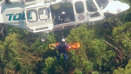 Specialist paramedics winch the injured man from heavy cover into the helicopter.