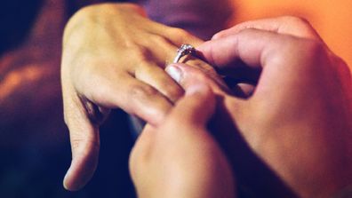 Man placing ring on woman's finger following proposal
