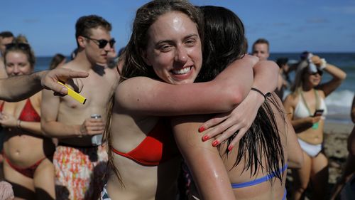 Two spring break revelers hug while partyng in a large crowd on the beach, Tuesday, March 17, 2020, in Pompano Beach, Fla. 